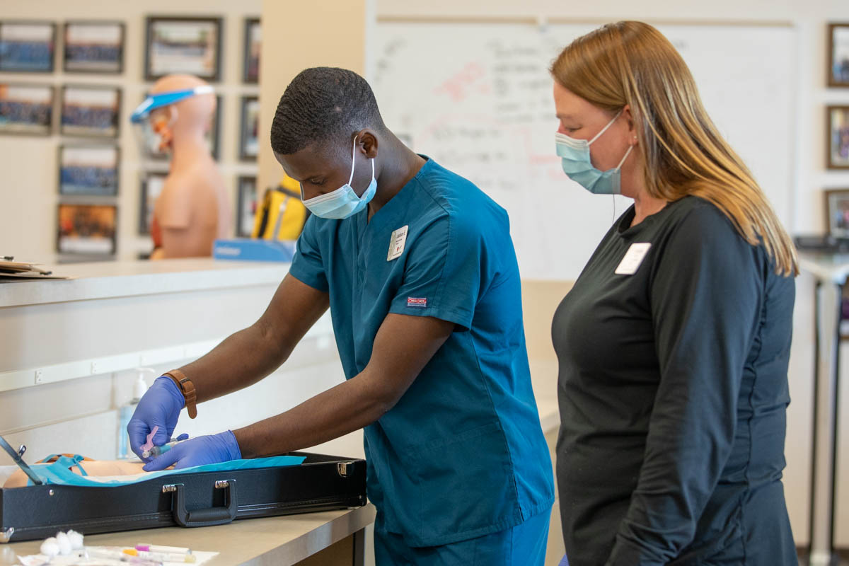 Instructor observing student drawing blood